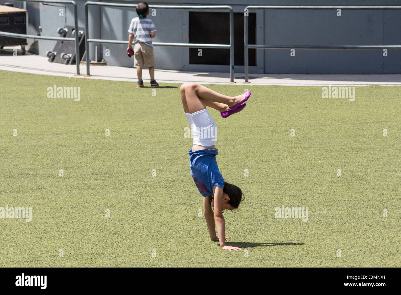 Young girl doing a handstand on the grass at Harbourfront Centre in Toronto Ontario Canada Stock Photo