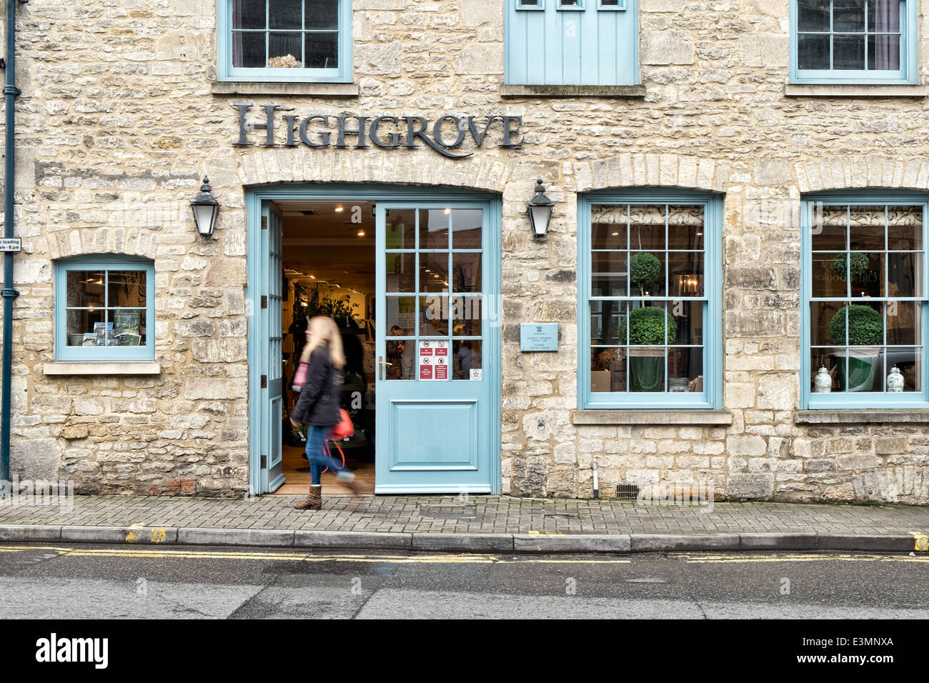 A woman, motion blurred walks past the front door of Prince Charles's Highgrove store in the Cotswold town of Tetbury Stock Photo
