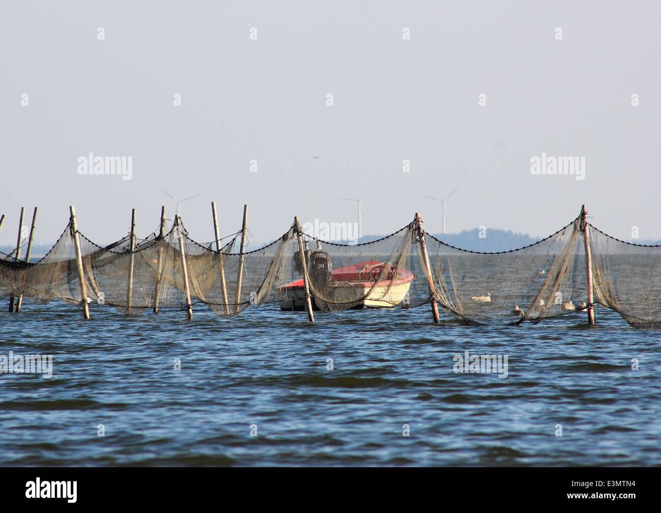 Small boat near offshore fishing net and traps Stock Photo