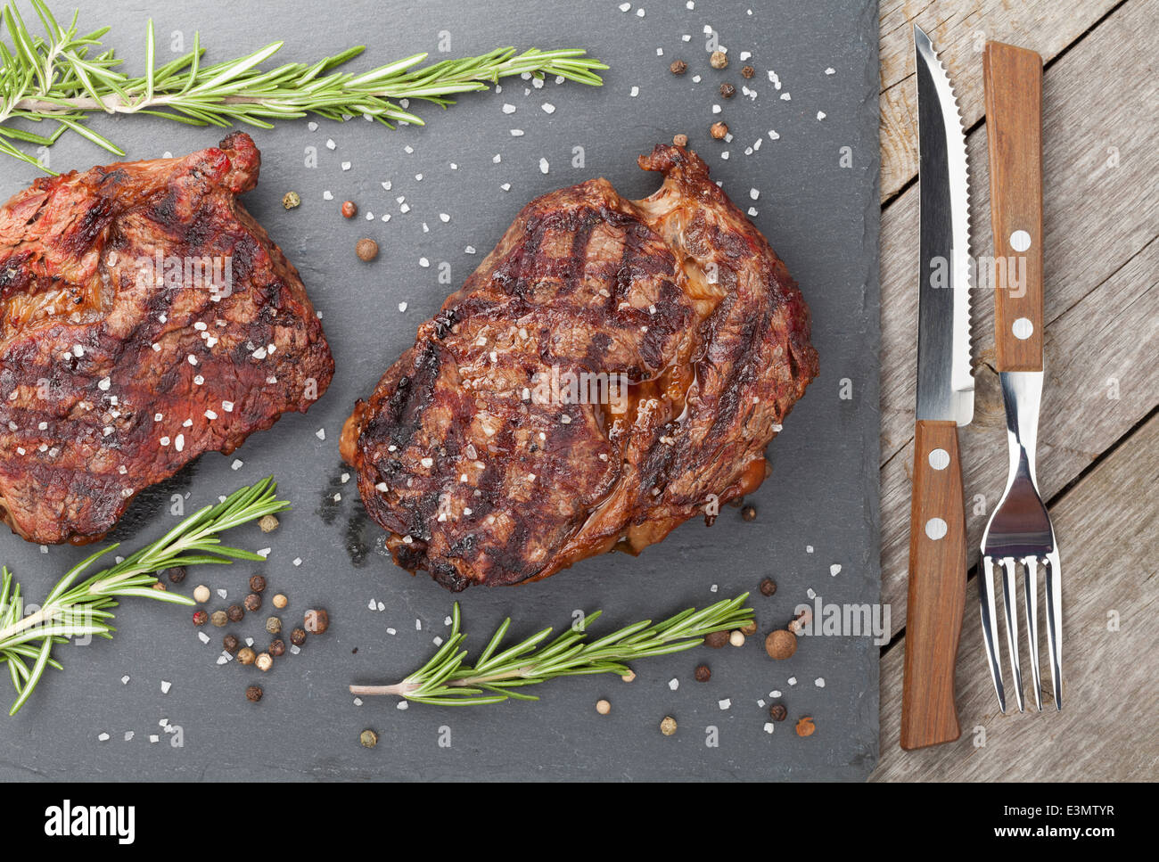 Beef steaks with rosemary and spices on wooden table Stock Photo