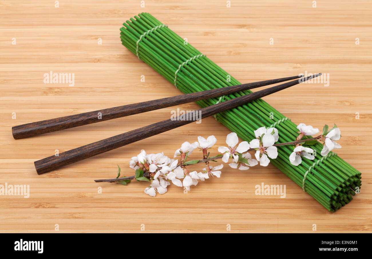 Chopsticks and sakura branch over bamboo mat Stock Photo