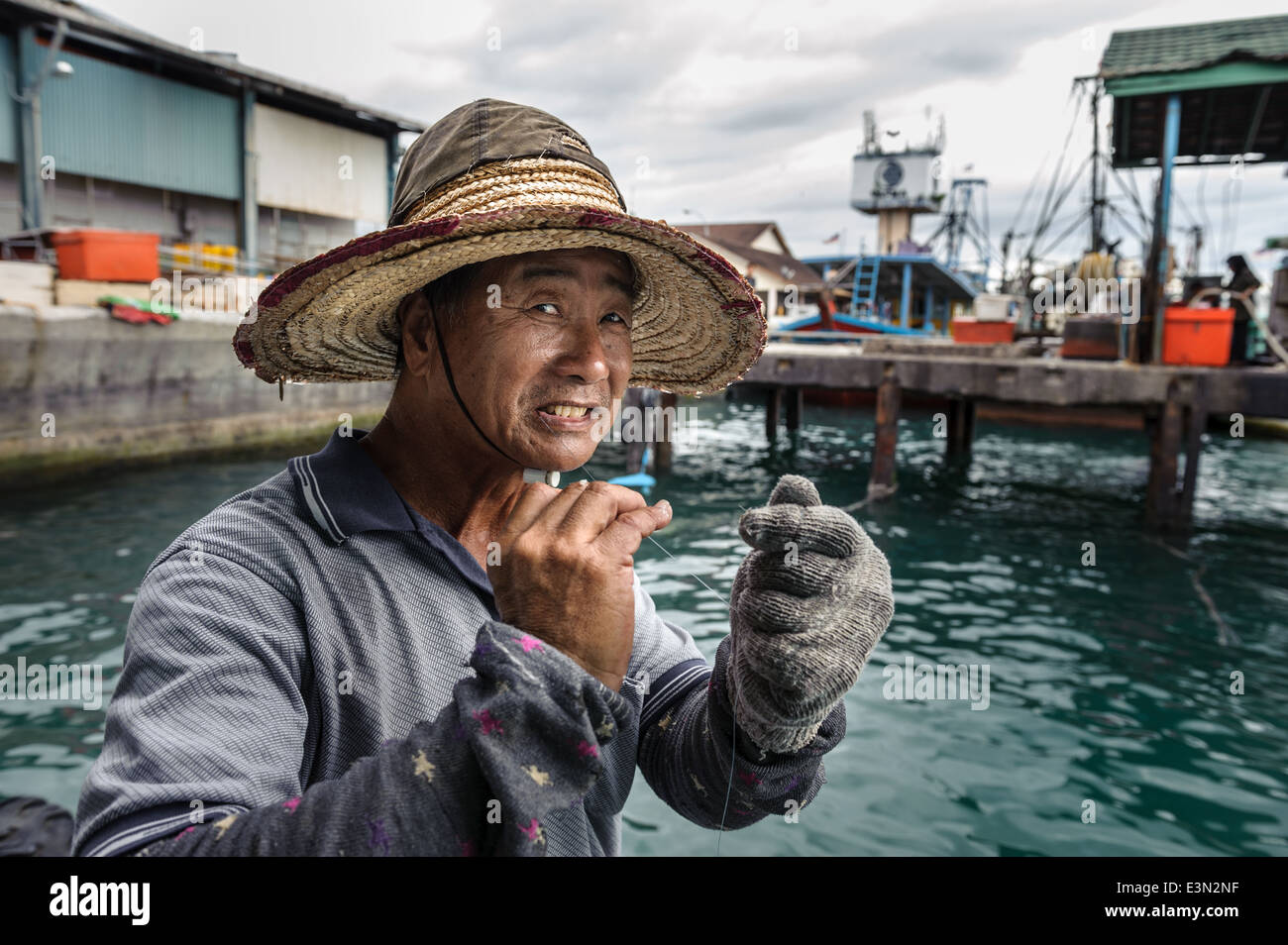 Fisherman cutting a fishing line with his teeth, Borneo, Malaysia