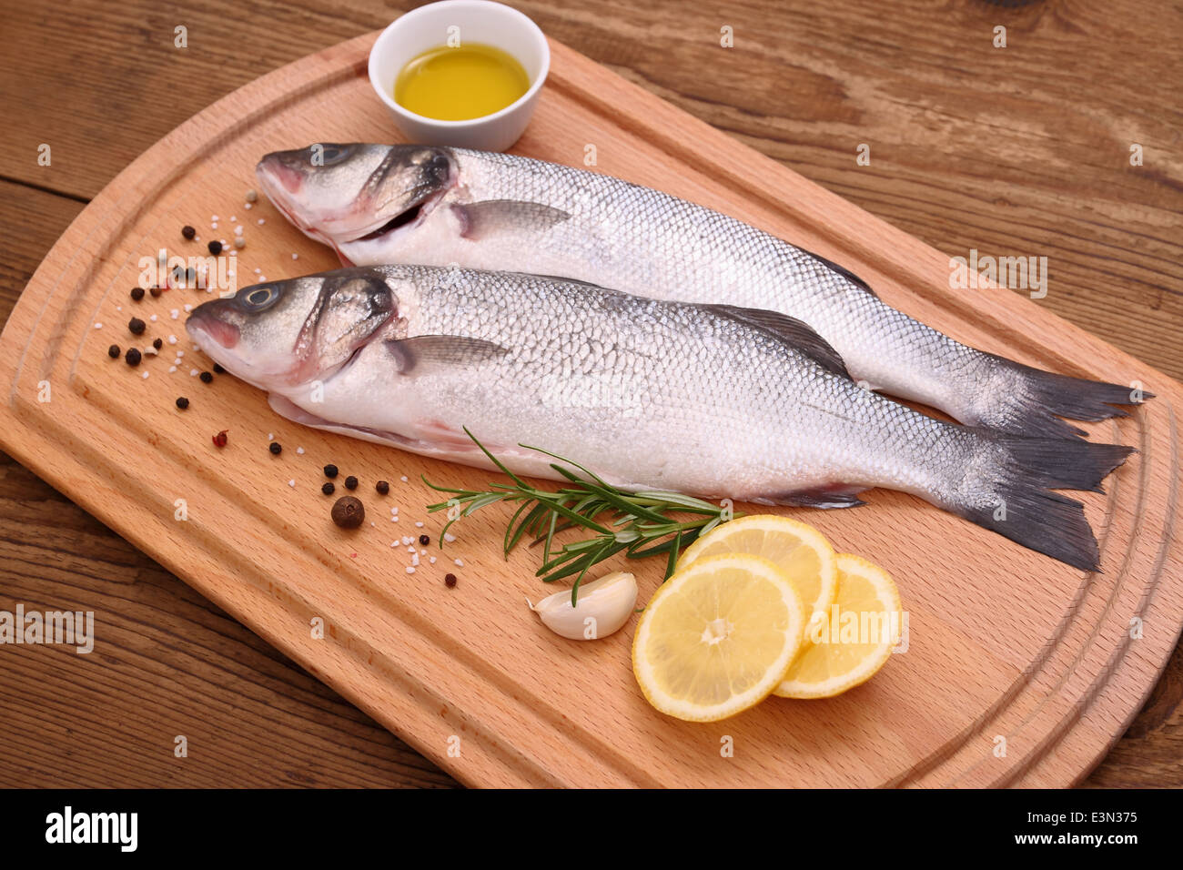 Two fresh sea bass fish on cutting board, top view Stock Photo