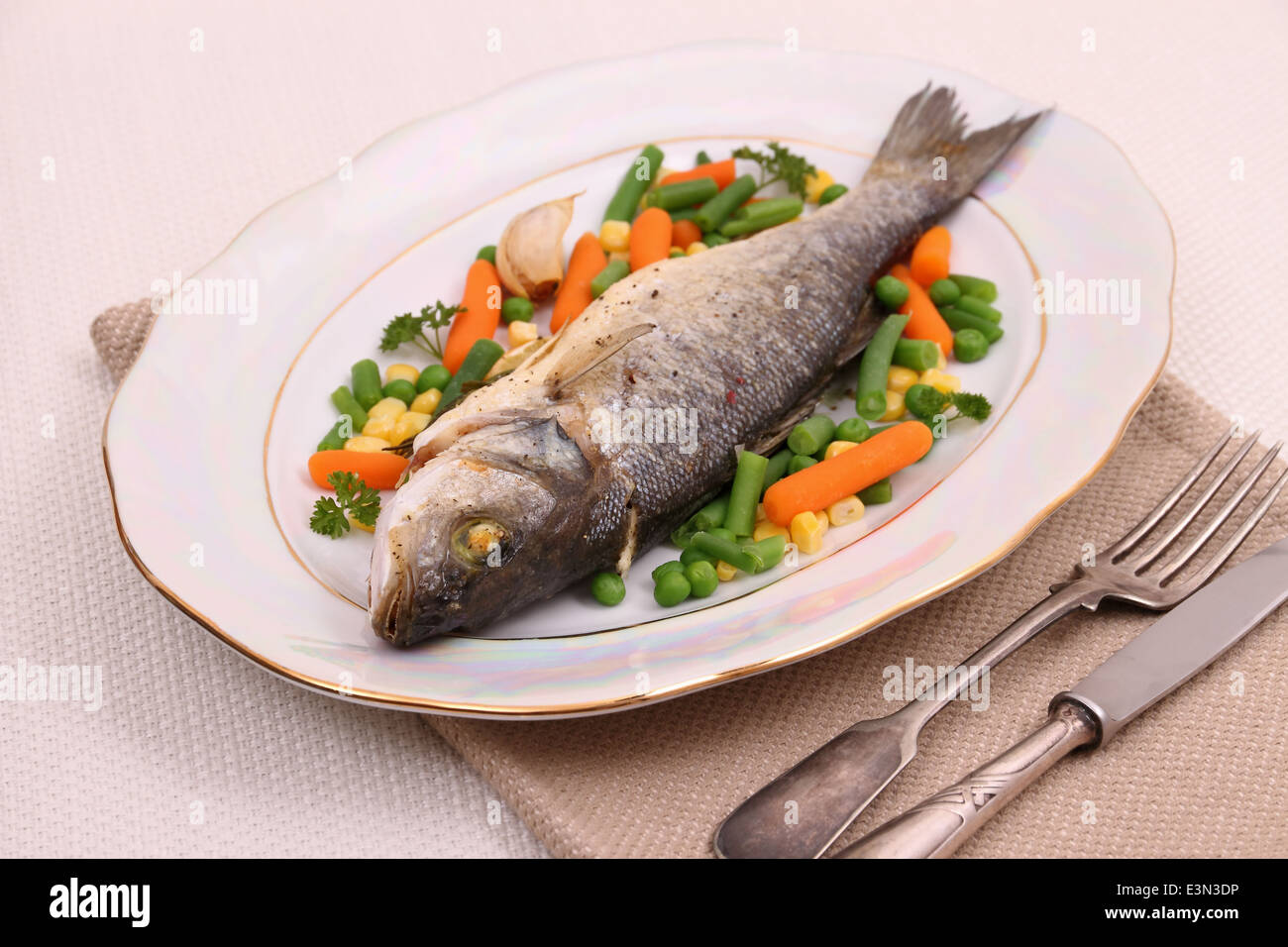 Grilled whole sea bass with vegetables and lemon, close up Stock Photo