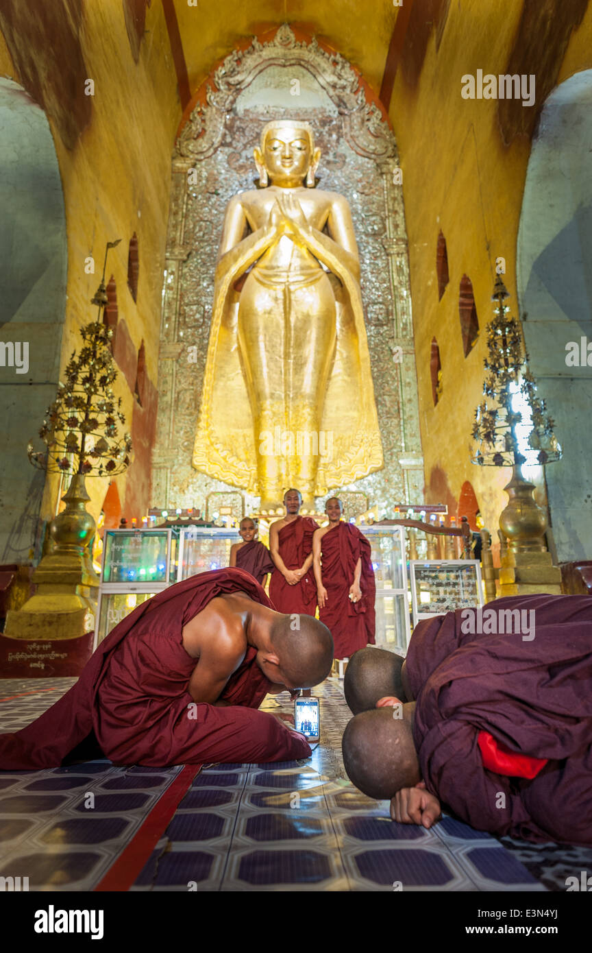 Group of monks taking pictures with a smart phone inside a temple, Bagan, Myanmar, Asia Stock Photo