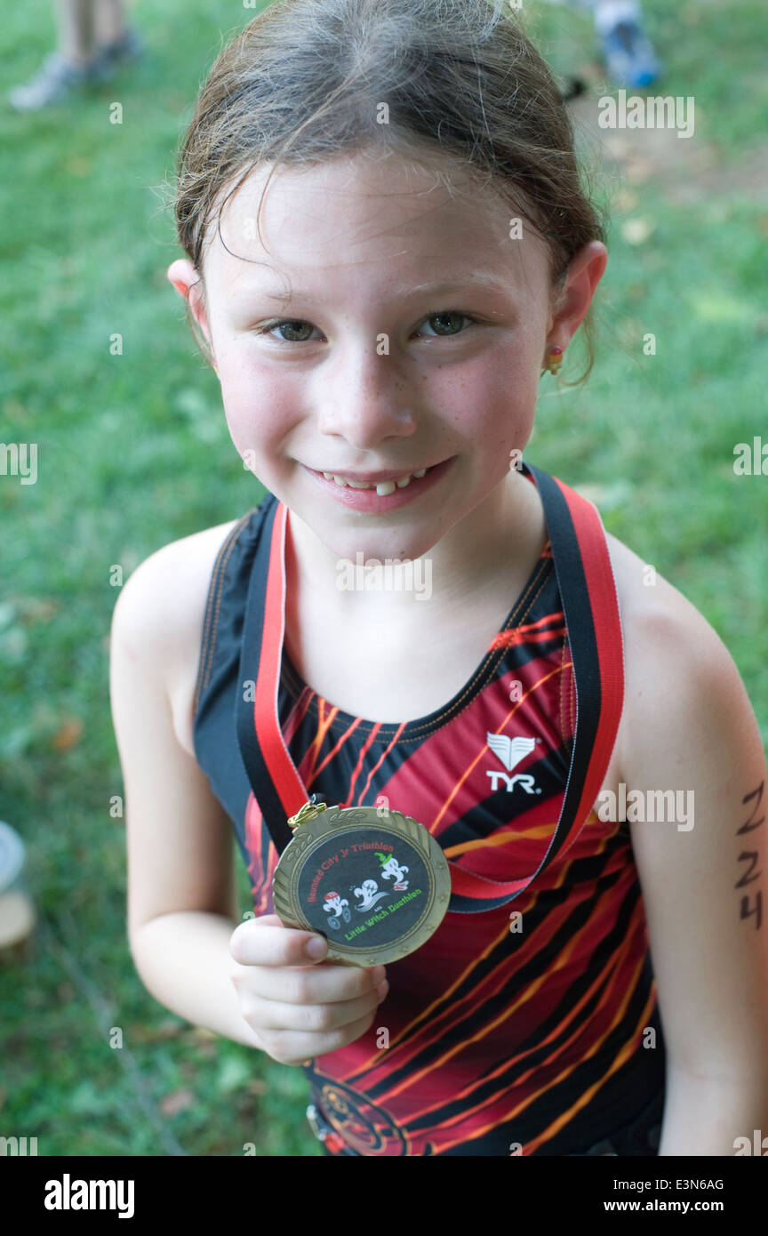 Eight year girl proudly displays her medal for participating in the