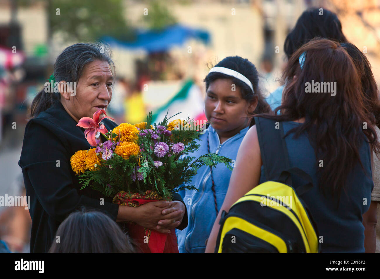 A woman carrying flowers during the DIA DE LOS LOCOS celebration - SAN MIGUEL DE ALLENDE, GUANAJUATO, MEXICO Stock Photo