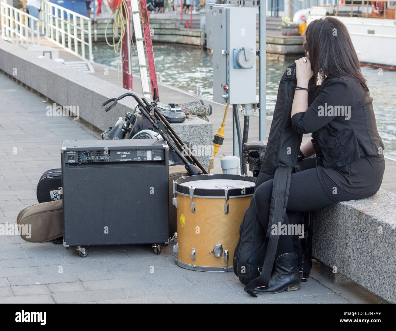 Street performer musician leaning on her cello with drum set all packed st Harbourftont on Toronto's Waterfront Stock Photo