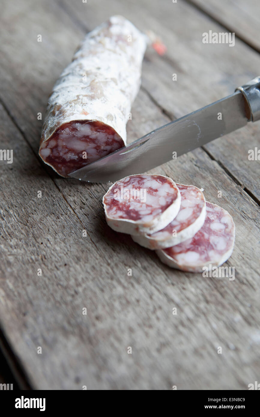Knife slicing sausage on table Stock Photo Alamy
