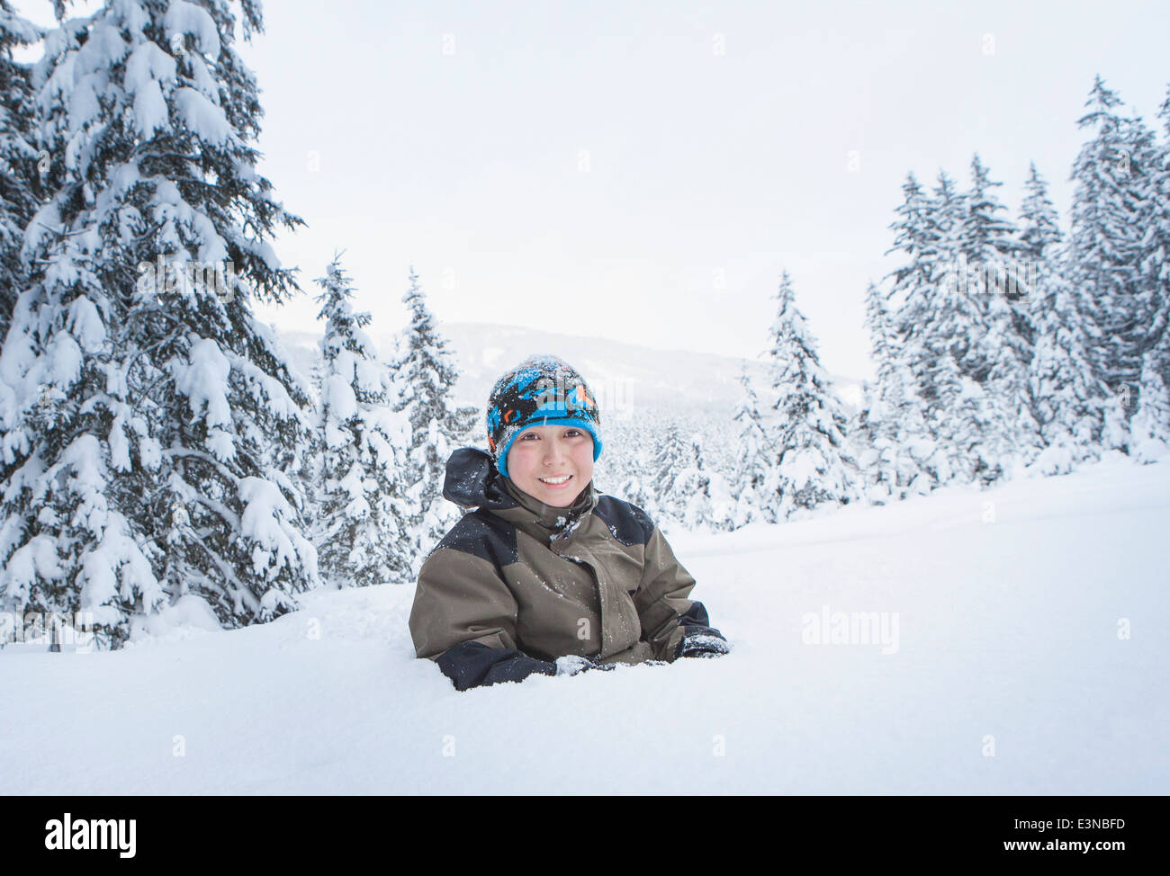 Portrait of smiling boy buried in snow Stock Photo