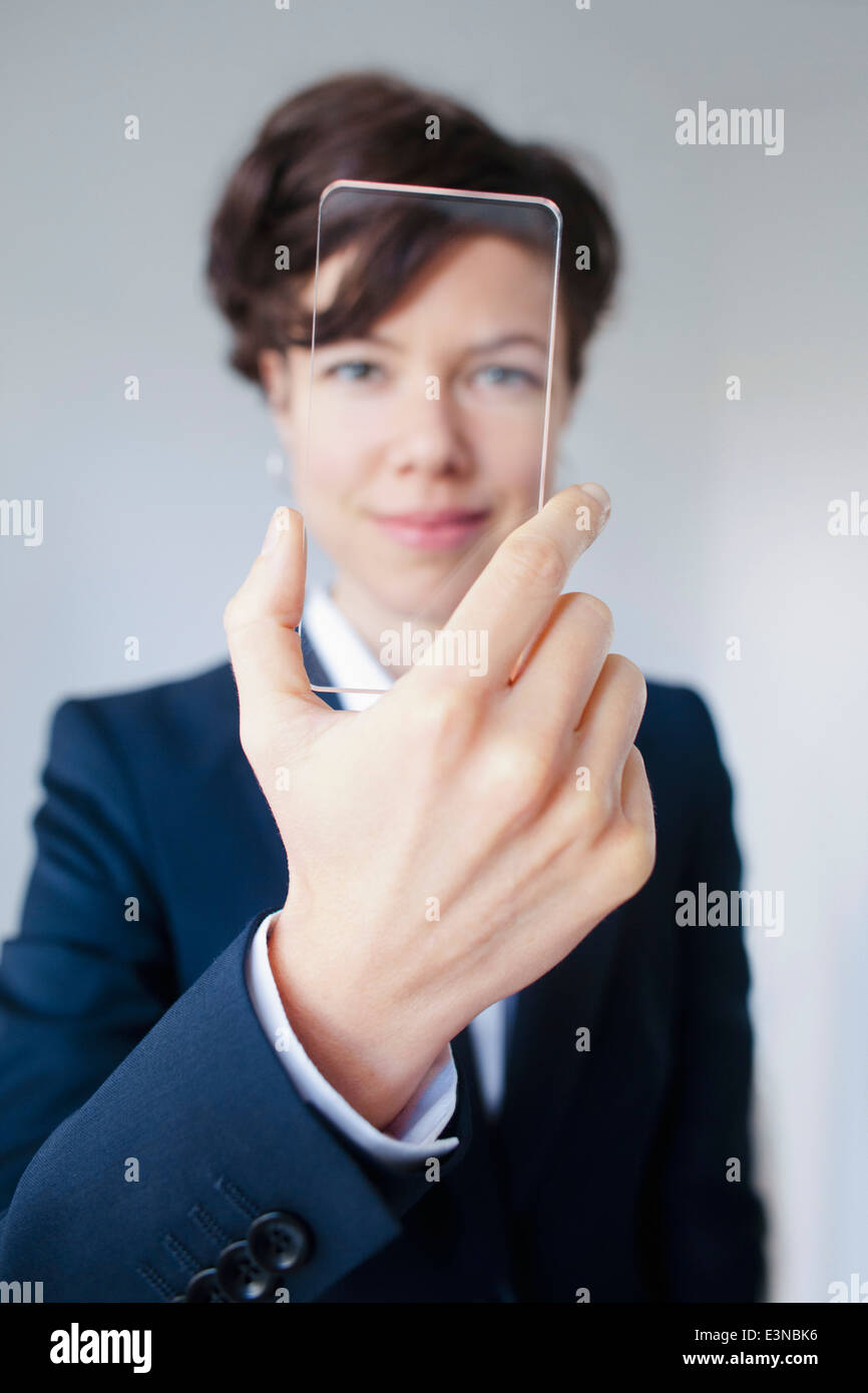 Confident Businesswoman Looking Through Futuristic Transparent Smartphone Stock Photo
