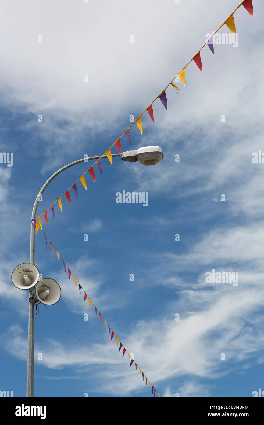 Low angle view of flags and street light with speakers against cloudy sky Stock Photo
