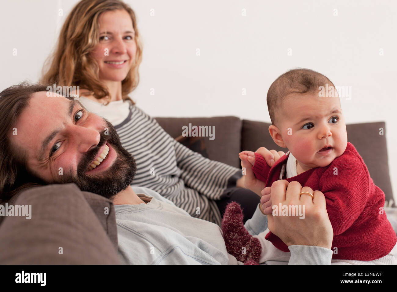 Portrait of happy parents with baby girl on sofa Stock Photo