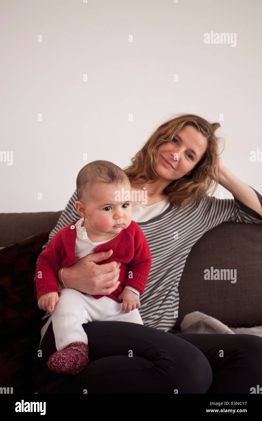 Portrait of woman sitting with baby girl on sofa at home Stock Photo