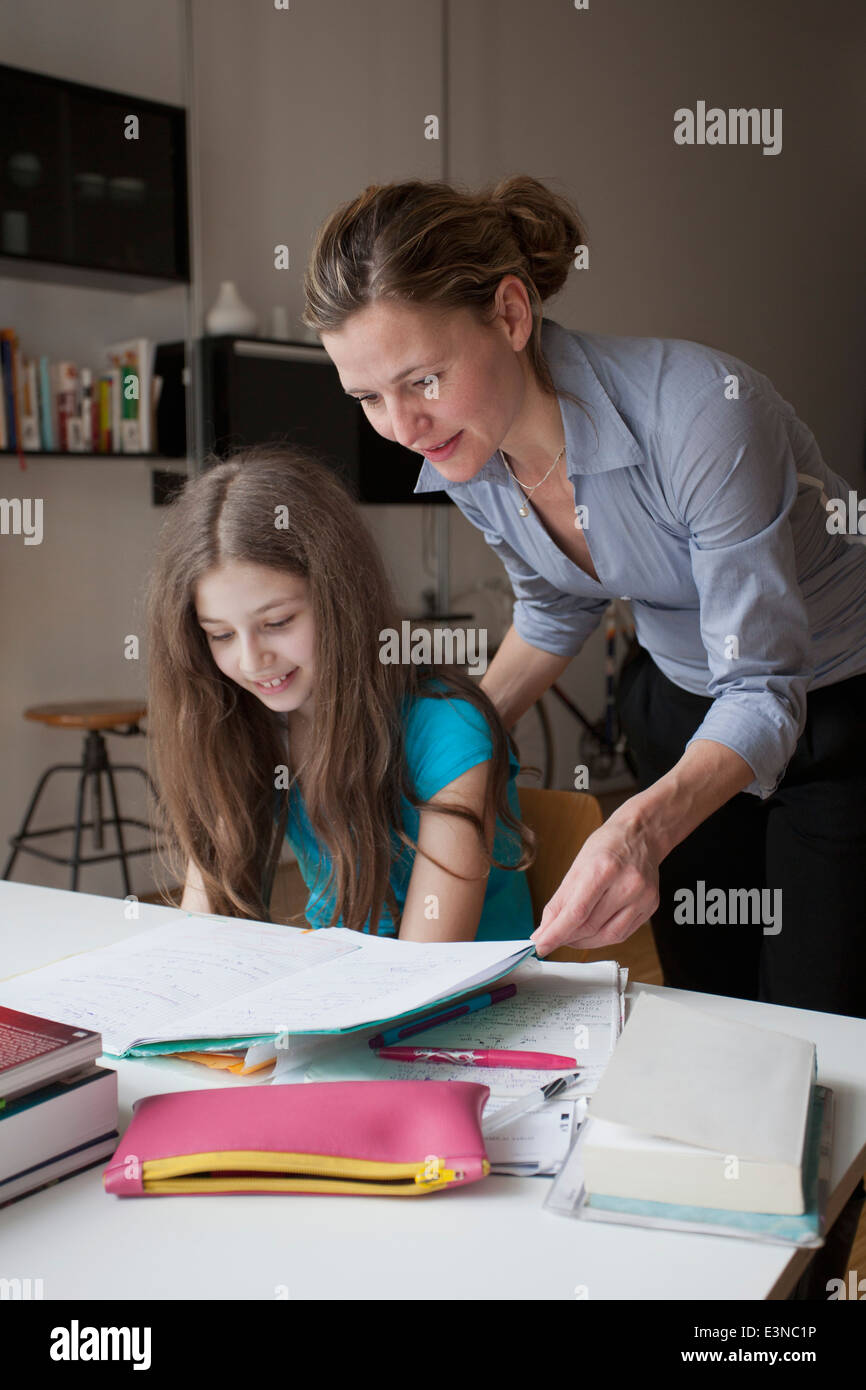 Mother helping daughter in doing homework at table Stock Photo - Alamy