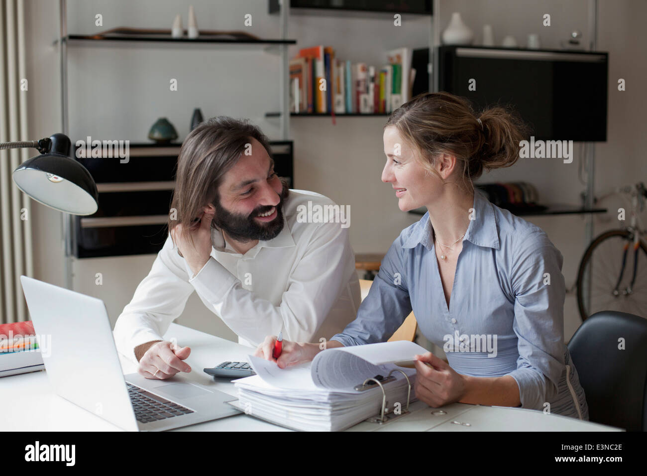 Mid adult couple looking at each other while working at home Stock Photo