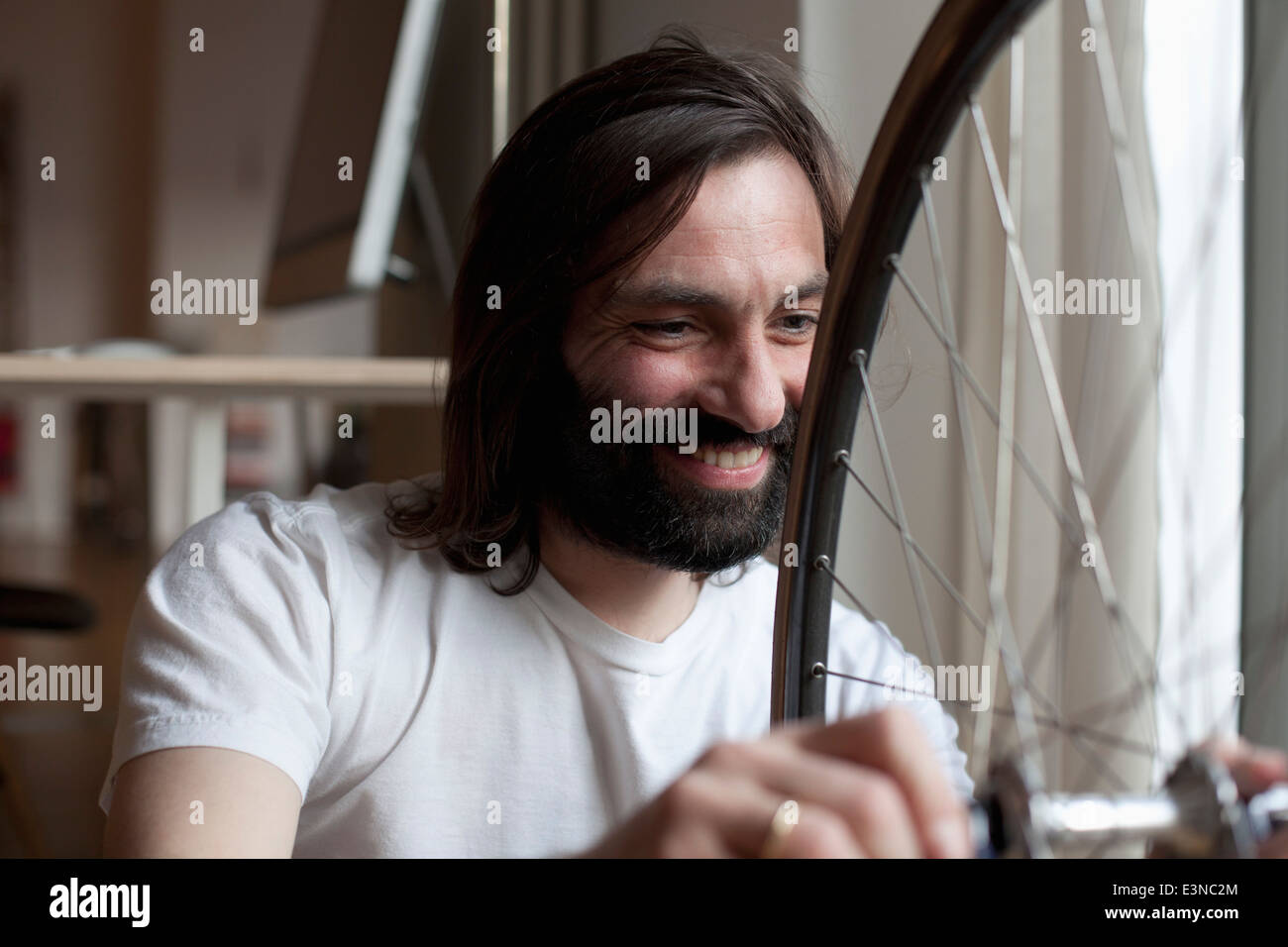 Smiling mid adult man repairing bicycle at home Stock Photo