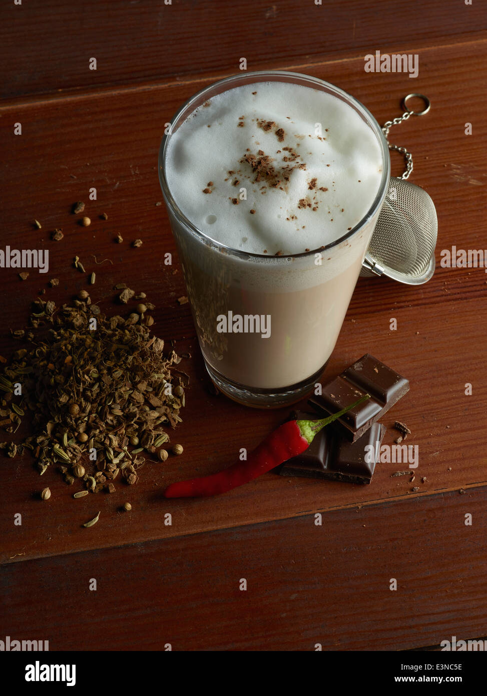 Chai latte surrounded by chocolate, chili, tea and spices Stock Photo