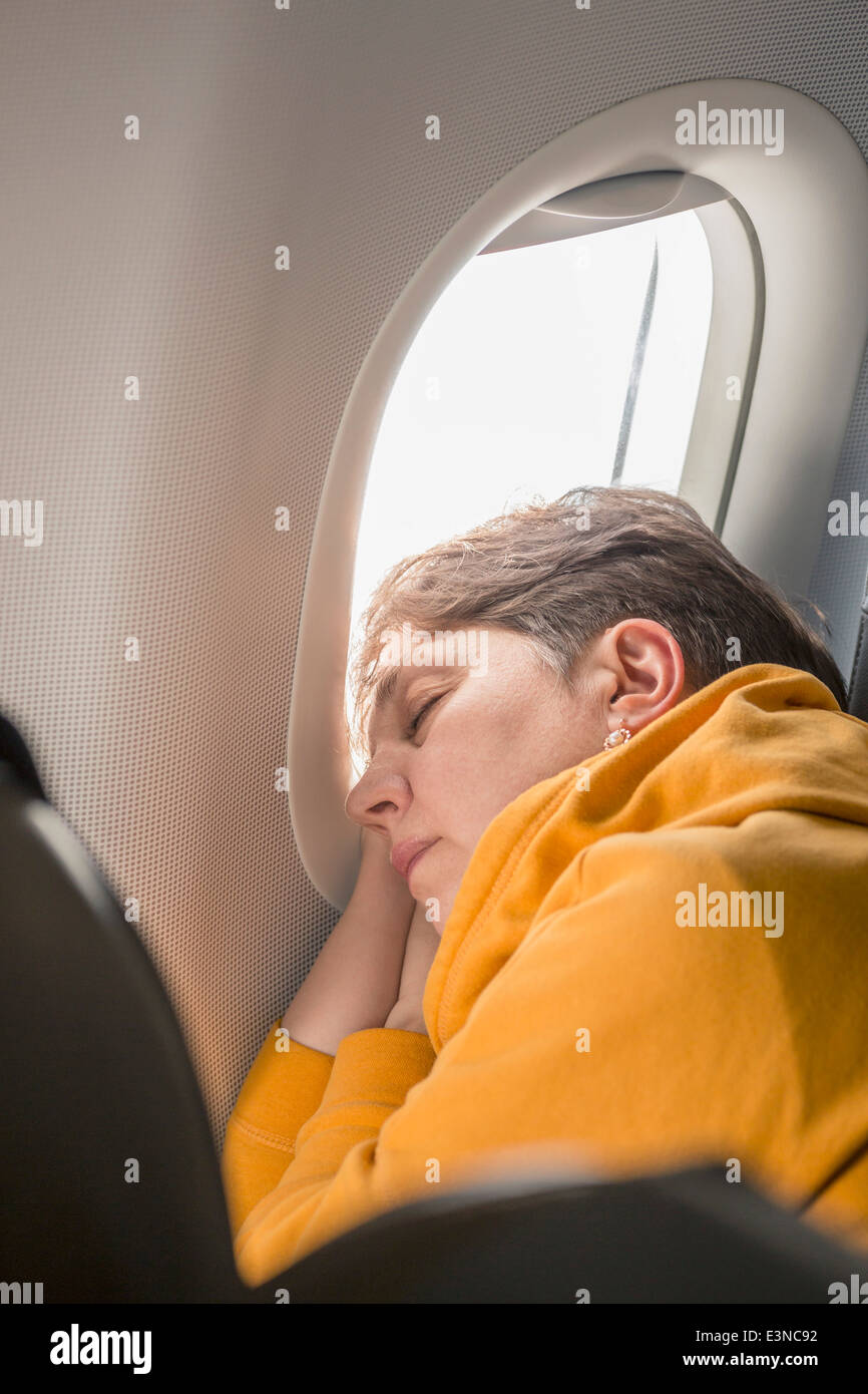 Mature woman sleeping in airplane Stock Photo