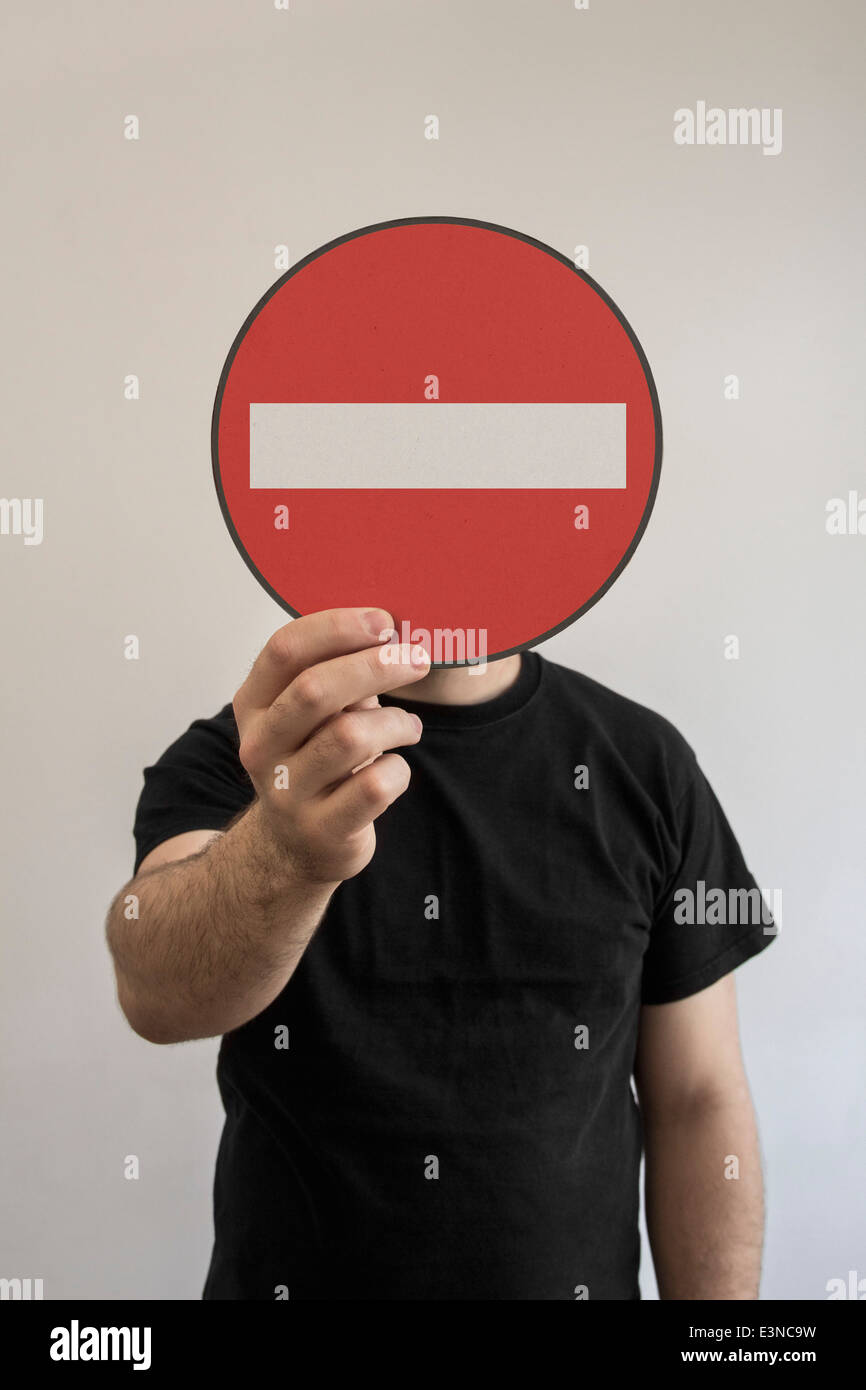 Man holding do not enter sign emoticon in front of his face Stock Photo
