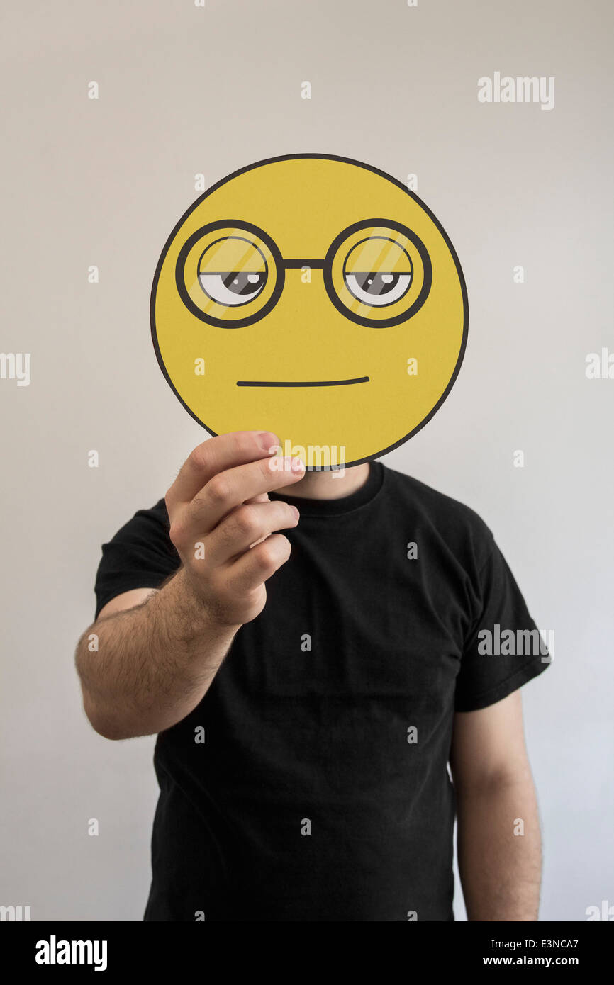 Man holding a nerdy face emoticon face in front of his face Stock Photo