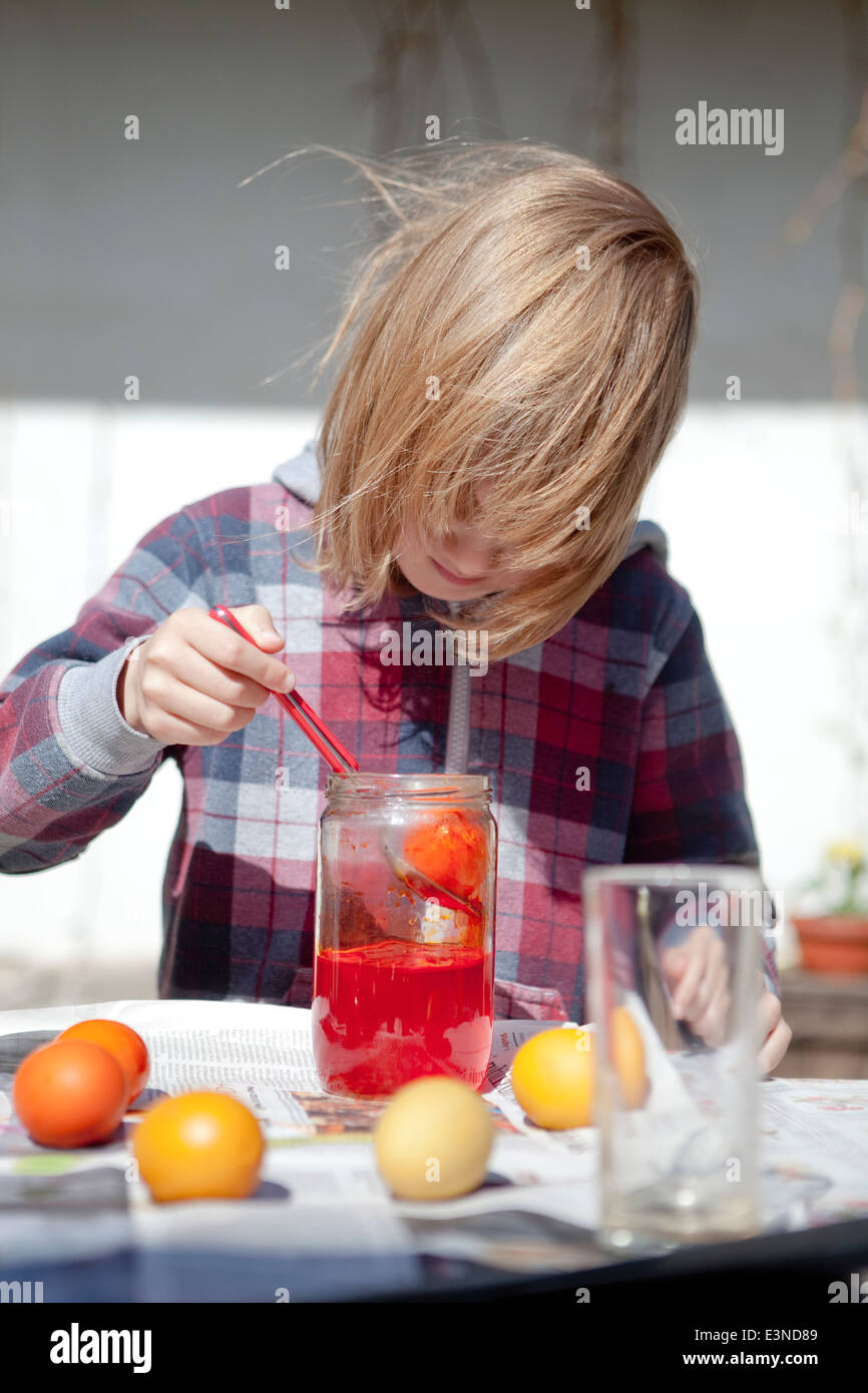 Boy Coloring Easter Eggs by Putting Them in Glasses with Color Stock Photo