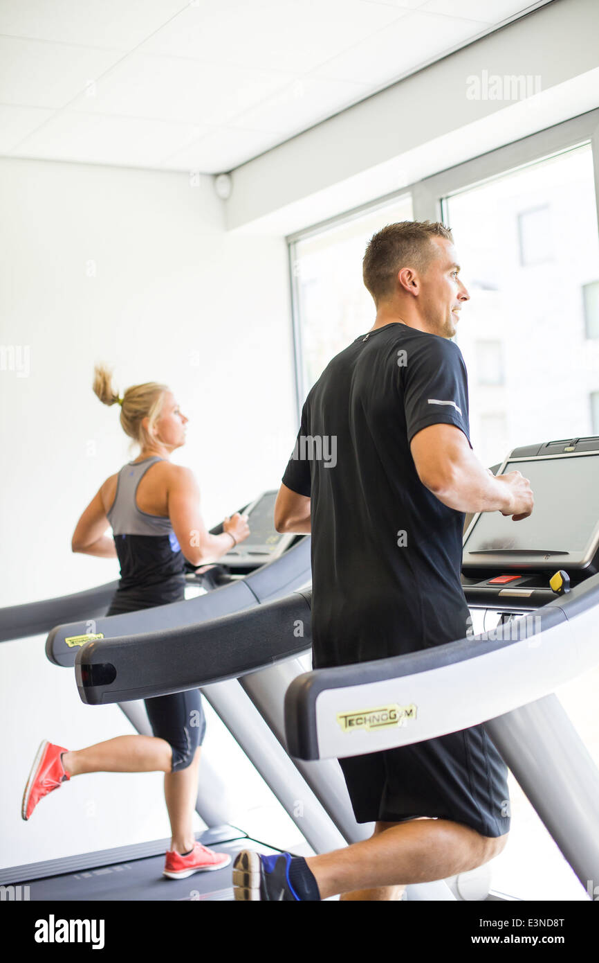 Healthy man and woman running on a treadmill in a gym Stock Photo - Alamy
