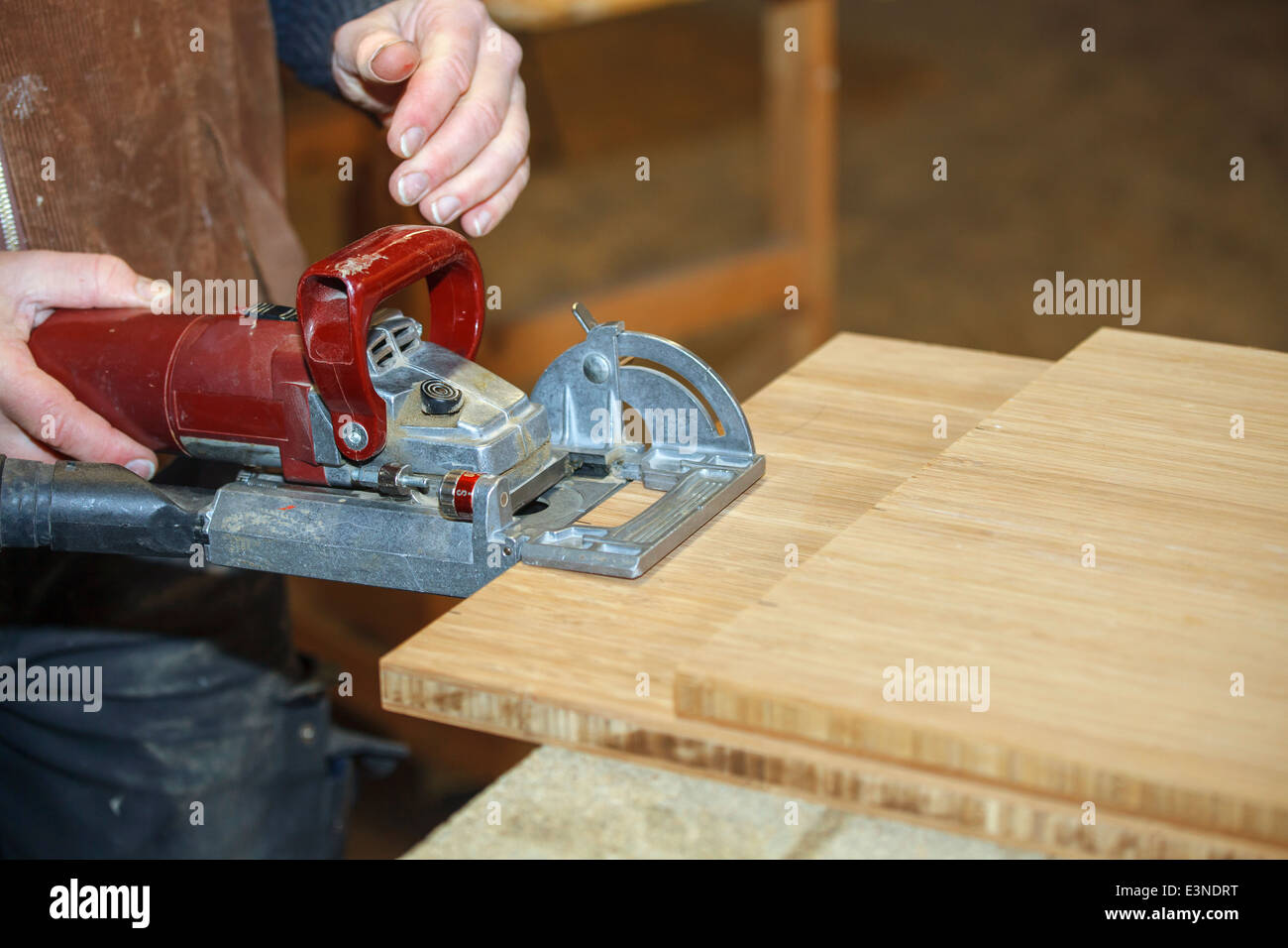 Close up of a carpenters hand working a plate joiner machine in the workshop Stock Photo