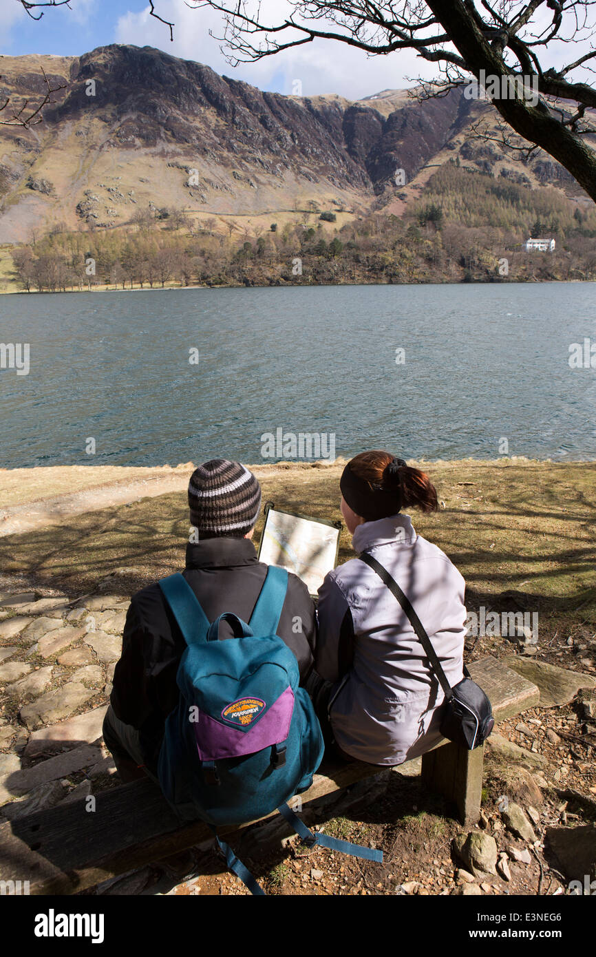 UK, Cumbria, Lake District, Buttermere, couple looking at map whilst sat on lakeside seat Stock Photo