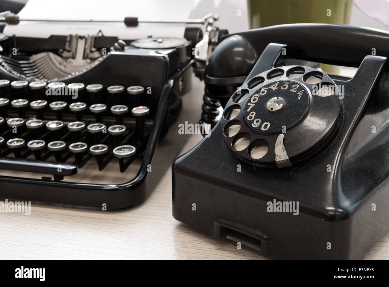 Vintage telephone and typewriter standing on the desk in the office