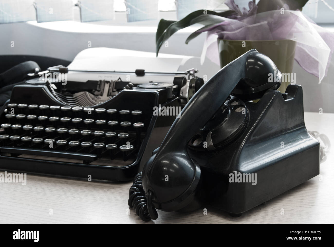 Vintage telephone and typewriter standing on the desk in the office