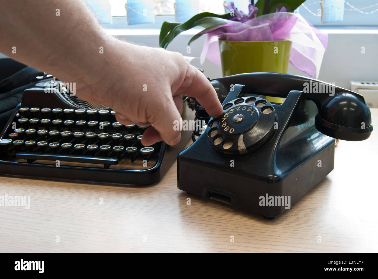 Vintage telephone and typewriter standing on the desk in the office