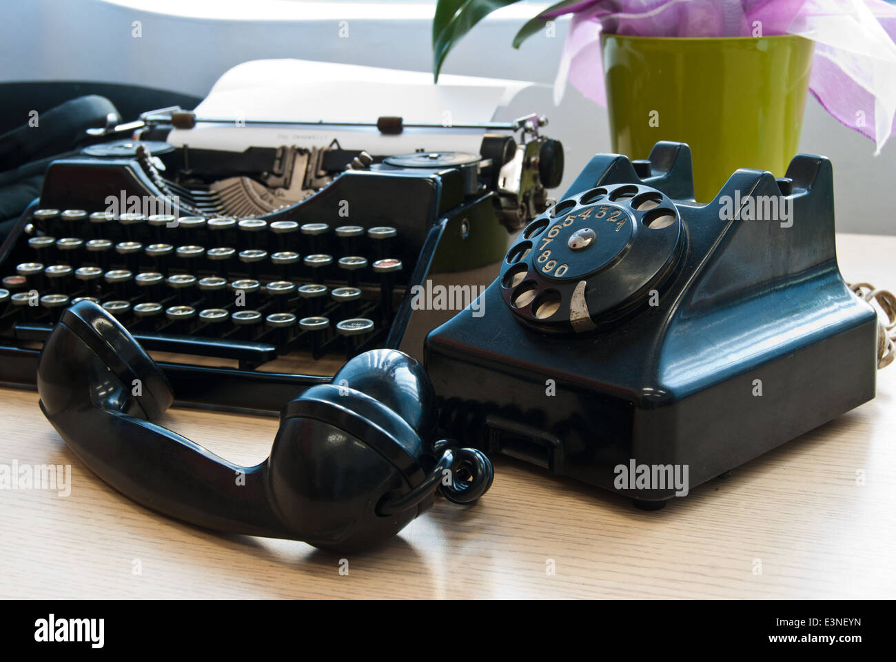 Vintage telephone and typewriter standing on the desk in the office