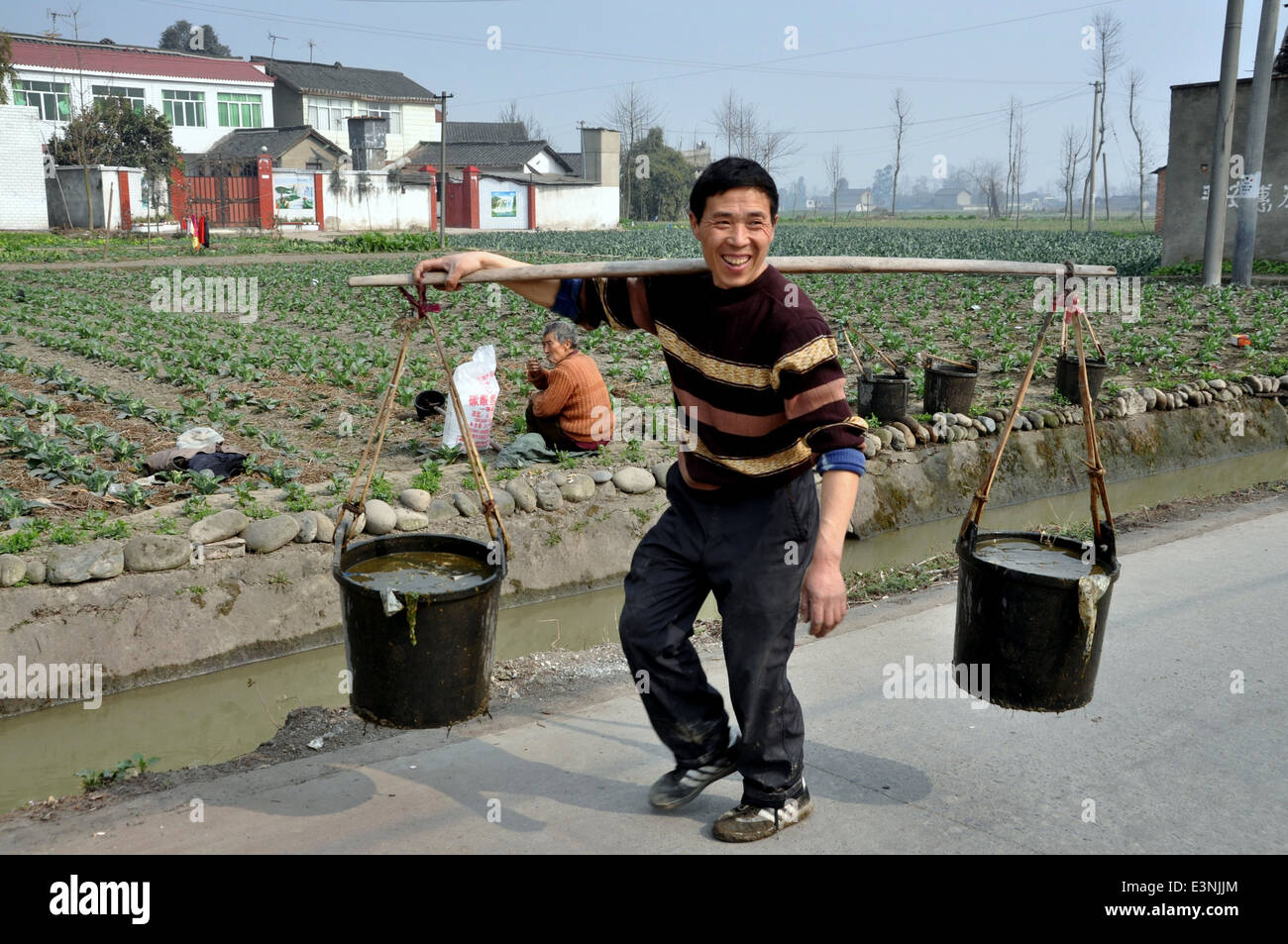 PENGZHOU, CHINA Farmer carrying two pails of water suspended from a