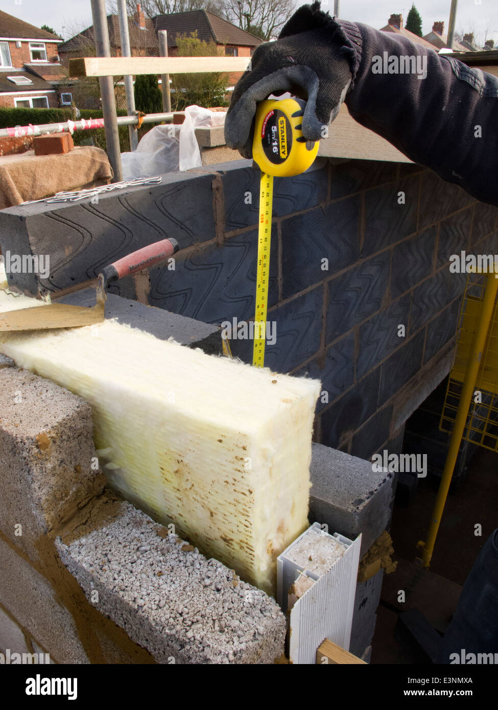 self building house, builder measuring block courses around insulated