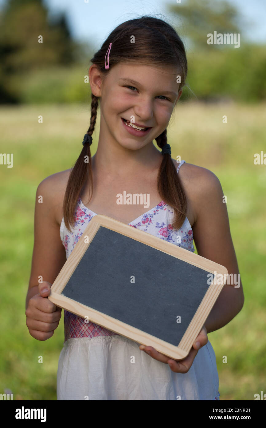 Portrait of a happy smiling young girl holding a small blackboard Stock ...
