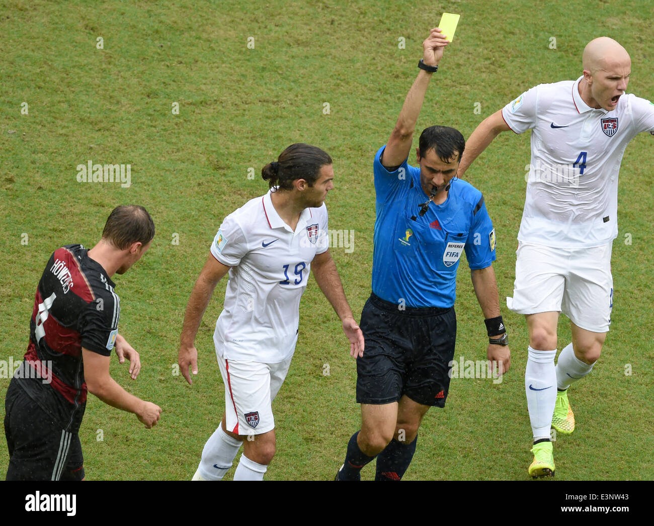 Recife, Brazil. 26th June, 2014. Referee Ravshan Irmatov shows a yellow card to Benedikt Hoewedes (L) of Germany during the FIFA World Cup group G preliminary round match between the USA and Germany at the Arena Pernambuco in Recife, Brazil, 26 June 2014. Photo: Andreas Gebert/dpa/Alamy Live News Stock Photo