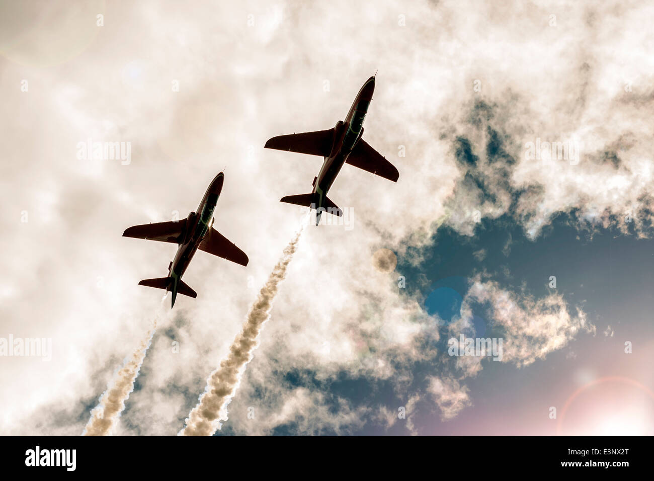 Two fighter jets fly in the cloudy sky, line of exhaust behind them Stock Photo