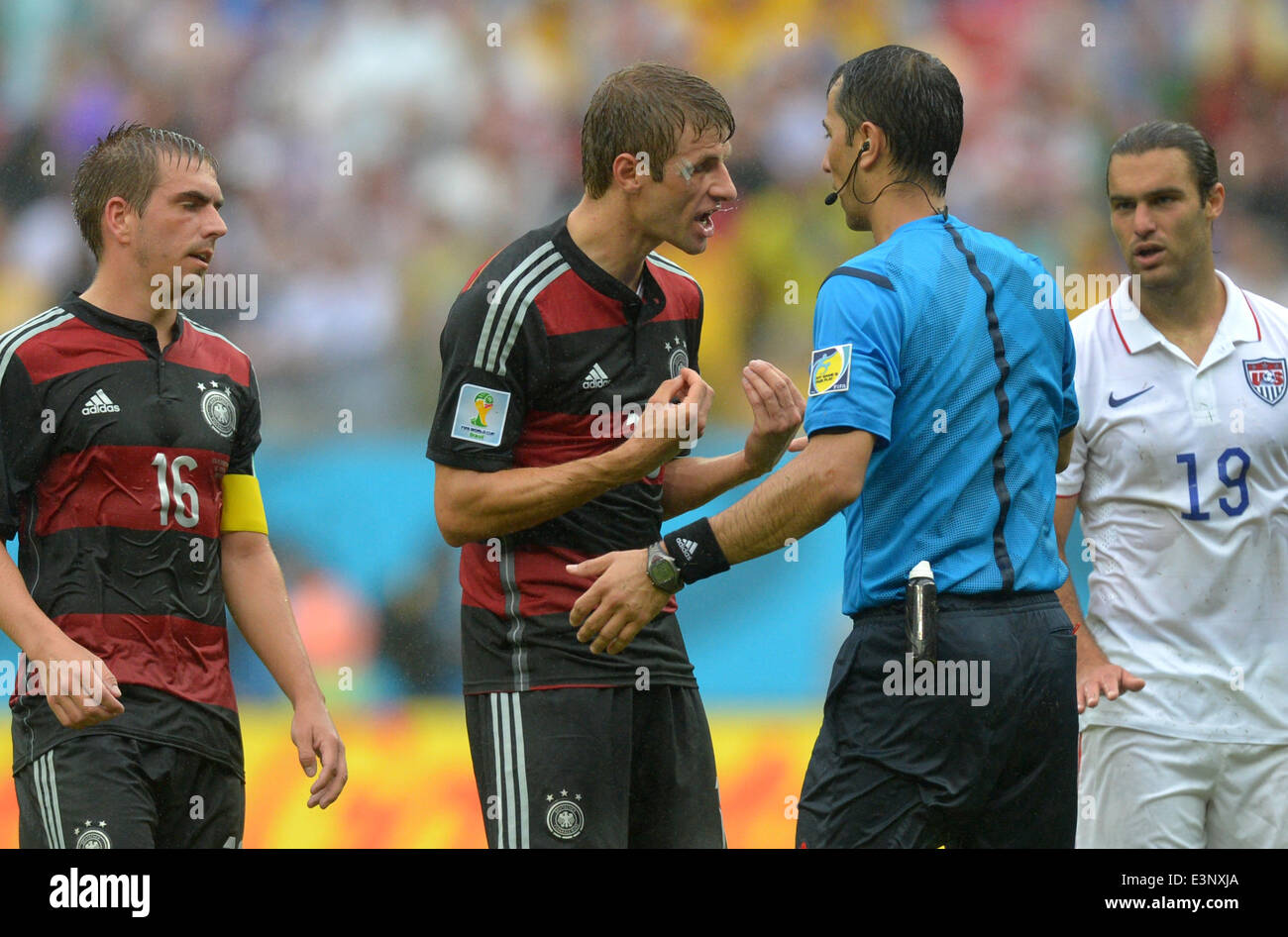 Recife, Brazil. 26th June, 2014. Germany's Philipp Lahm (L) and Thomas Mueller argue with referee Abduxamidullo Rasulov of Uzbekistan as Graham Zusi of the US looks on during the FIFA World Cup group G preliminary round match between the USA and Germany at Arena Pernambuco in Recife, Brazil, 26 June 2014. Photo: Thomas Eisenhuth/dpa/Alamy Live News Stock Photo