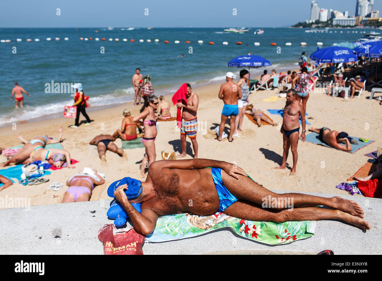 Foreign tourists sunbathing and relaxing on the beach in Pattaya, Thailand. Stock Photo
