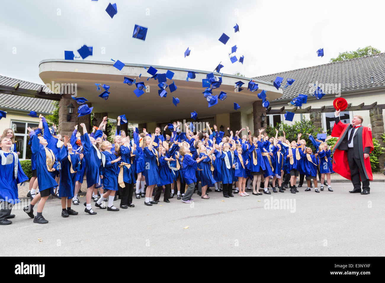 School children graduating from the UK's Children's University throw their mortar boards (hats) in the air in celebration Stock Photo