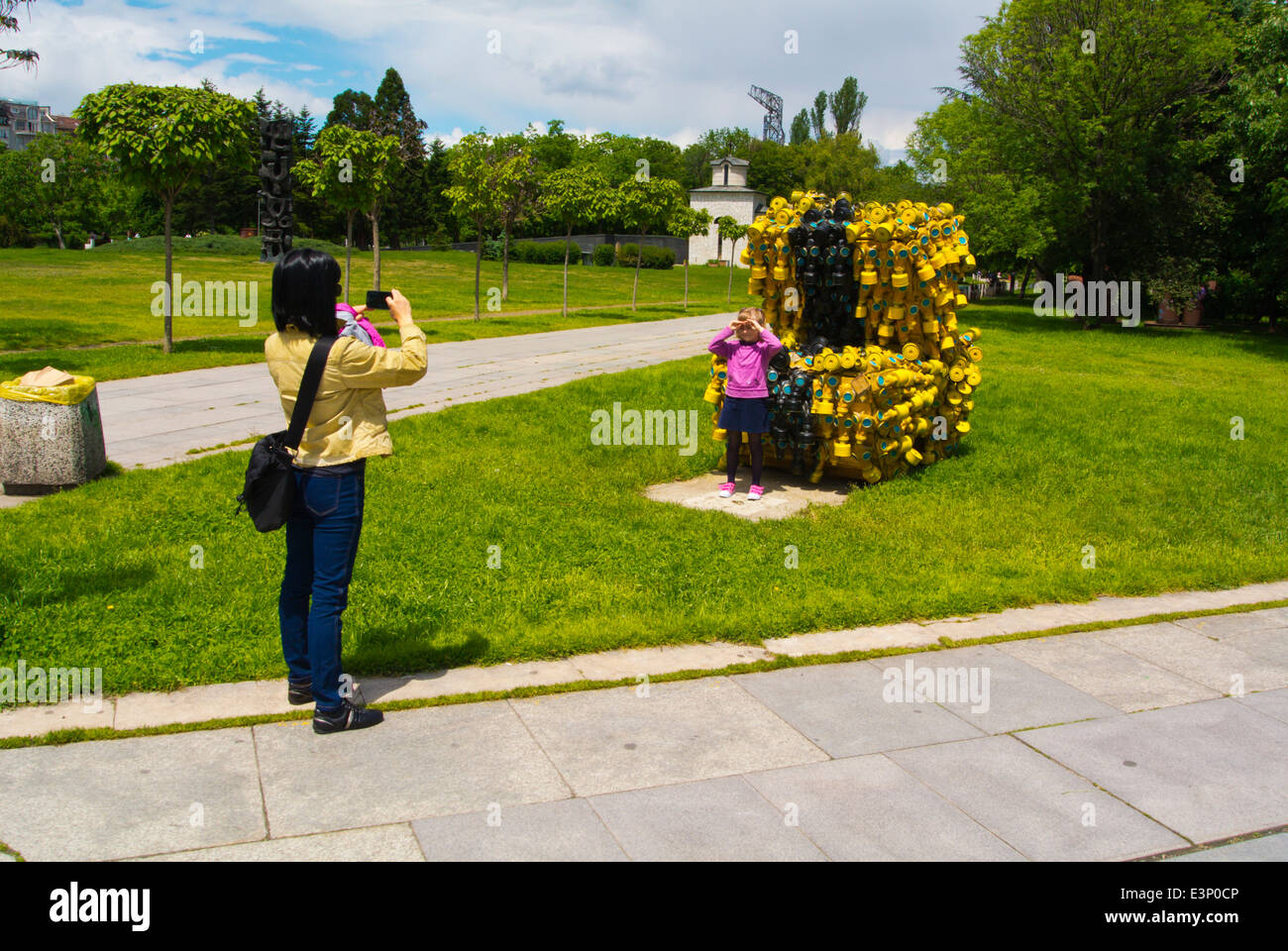 Mother photographing her child in front of sculpture made up of 400 gas masks on May 10 2014, NKD park, Sofia, Bulgaria Stock Photo