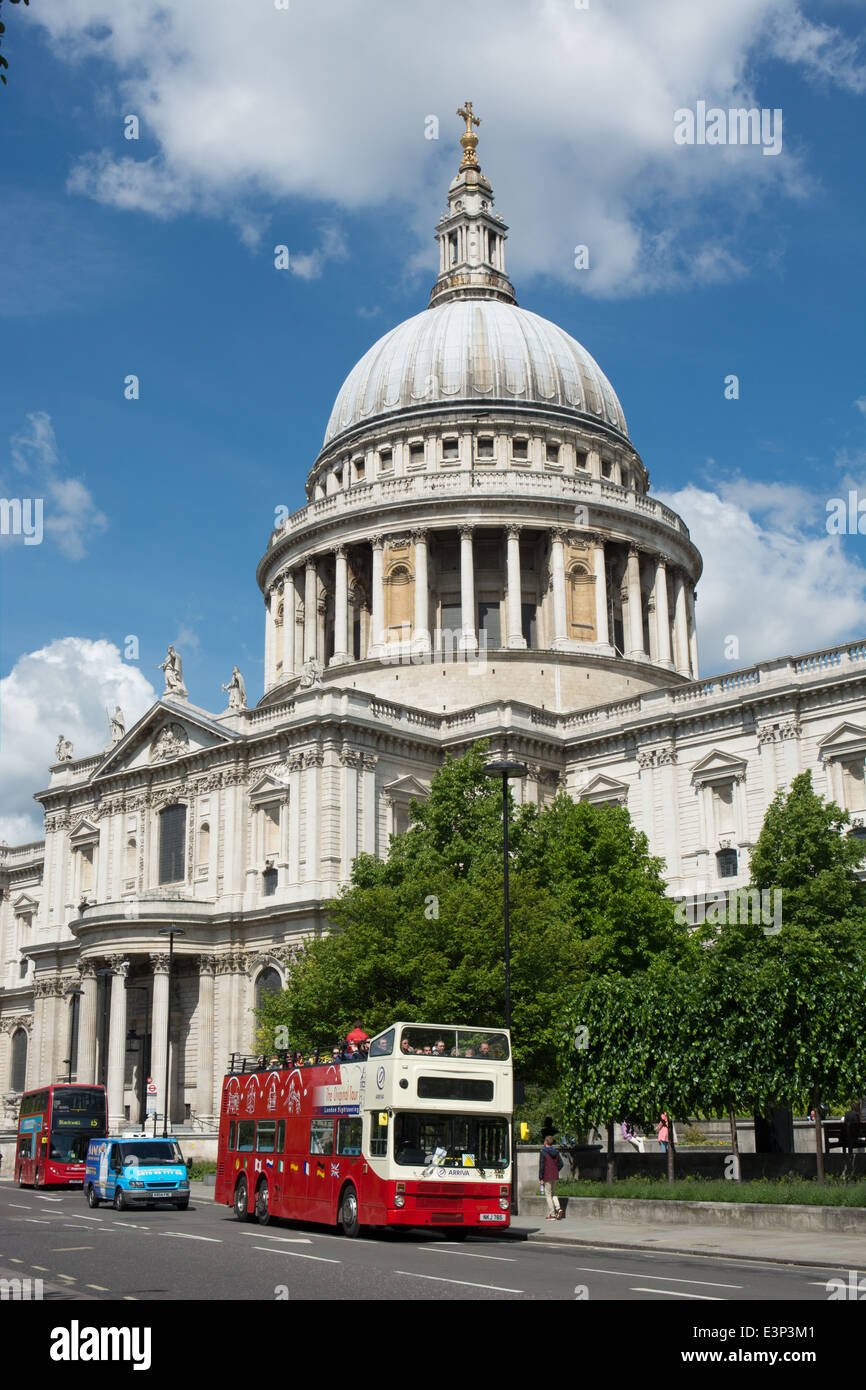 An open top double deck tour bus passes St Paul's cathedral on a sunny day Stock Photo