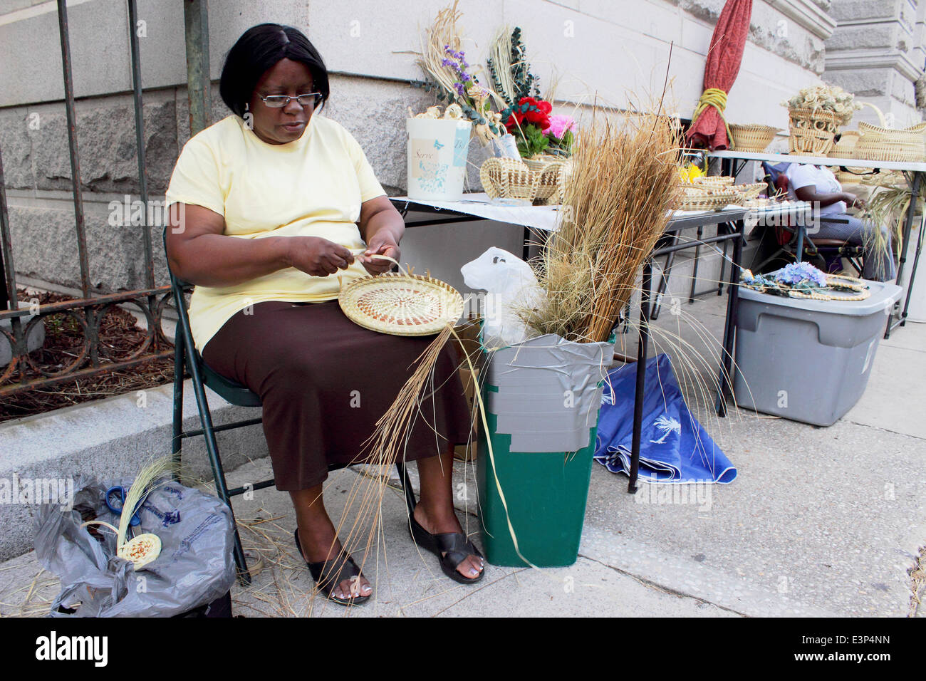 An African American woman weaves a sweet grass basket in Charlesto, South Carolina USA Stock Photo