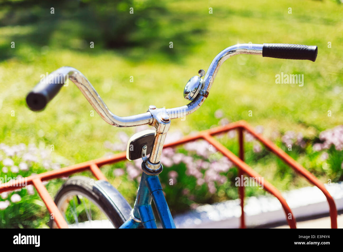 Vintage bicycle handlebar detail close up with parking bokeh background in flower bed in sunny day Stock Photo