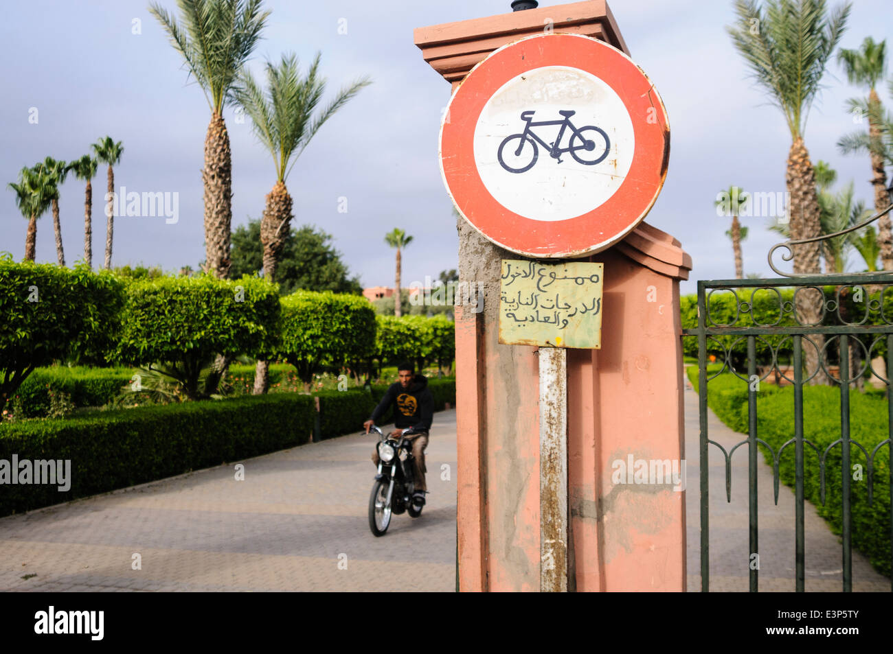 Man rides a scooter along a footpath with a sign saying 'No bicycles' in Marrakech, Morocco Stock Photo