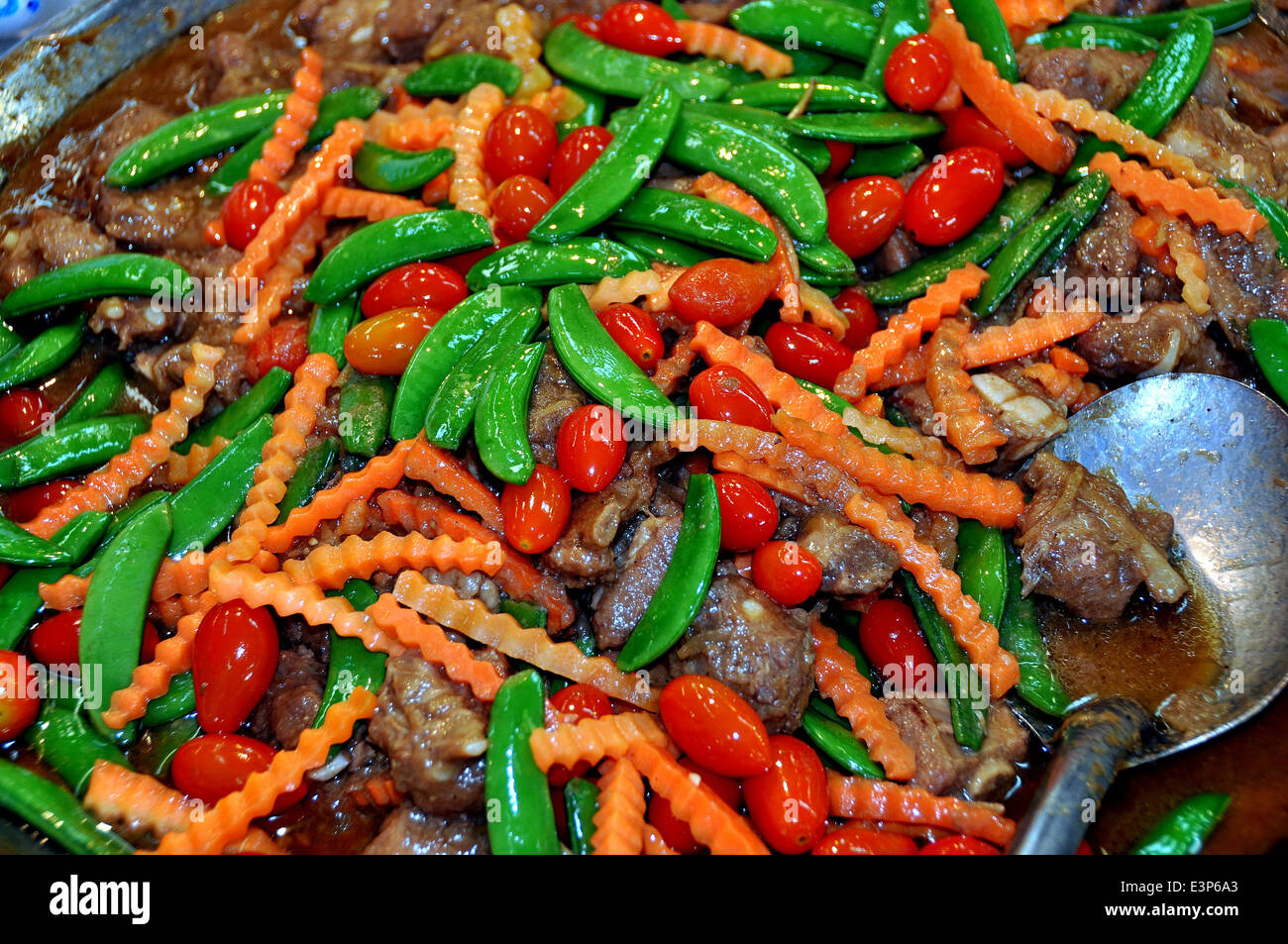 BANGKOK, THAILAND: Stir-fried beef, snow peas, cherry tomatoes, and julienne carrots tempts buyers at the Or Tor Kor Market Stock Photo