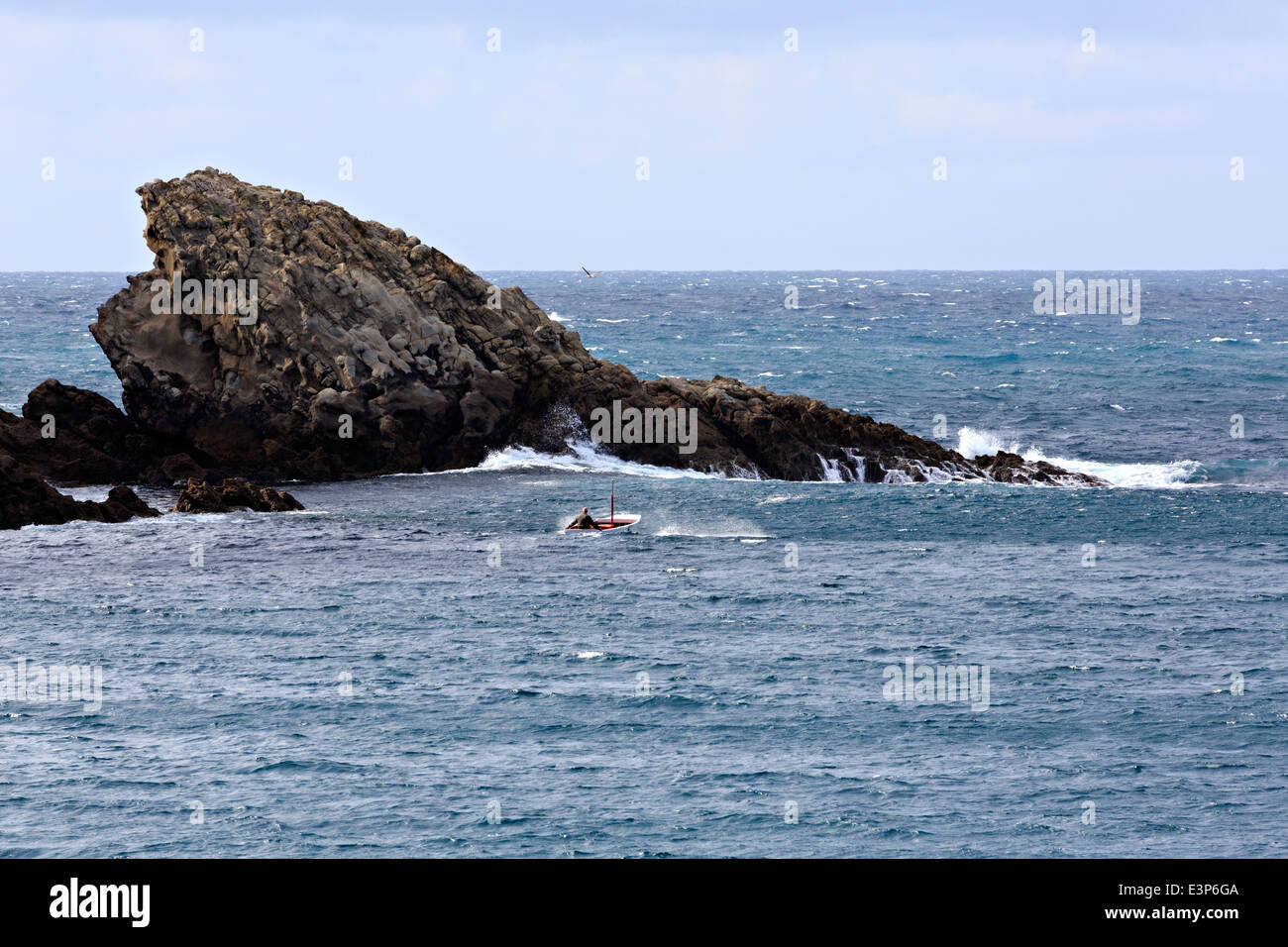 Getaria, Gipuzkoa, Basque Country, Spain. A local fisherman in a small boat braves the rough seas and rocky shoreline. Stock Photo