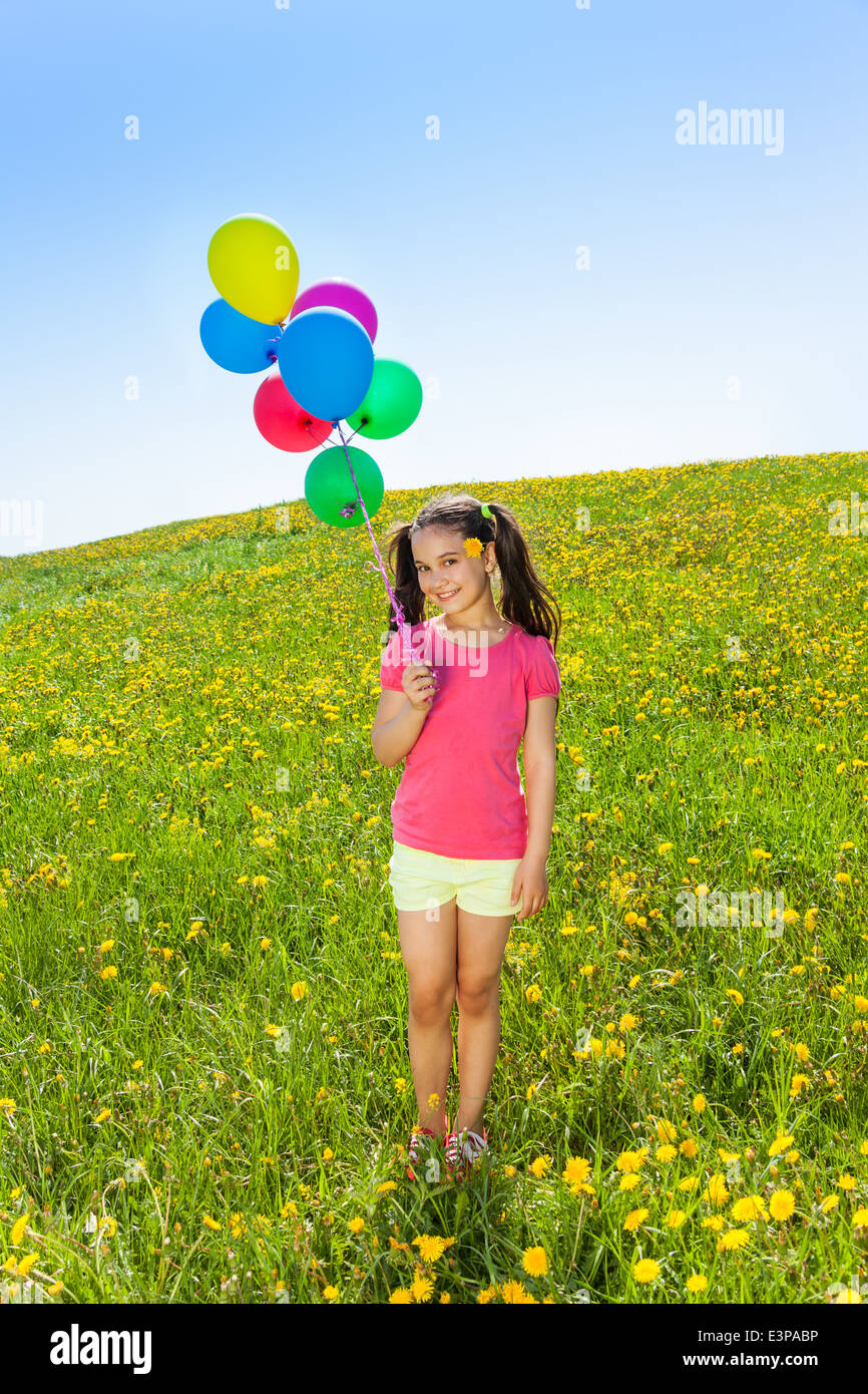 Cute girl with flying balloons stands on grass Stock Photo Alamy