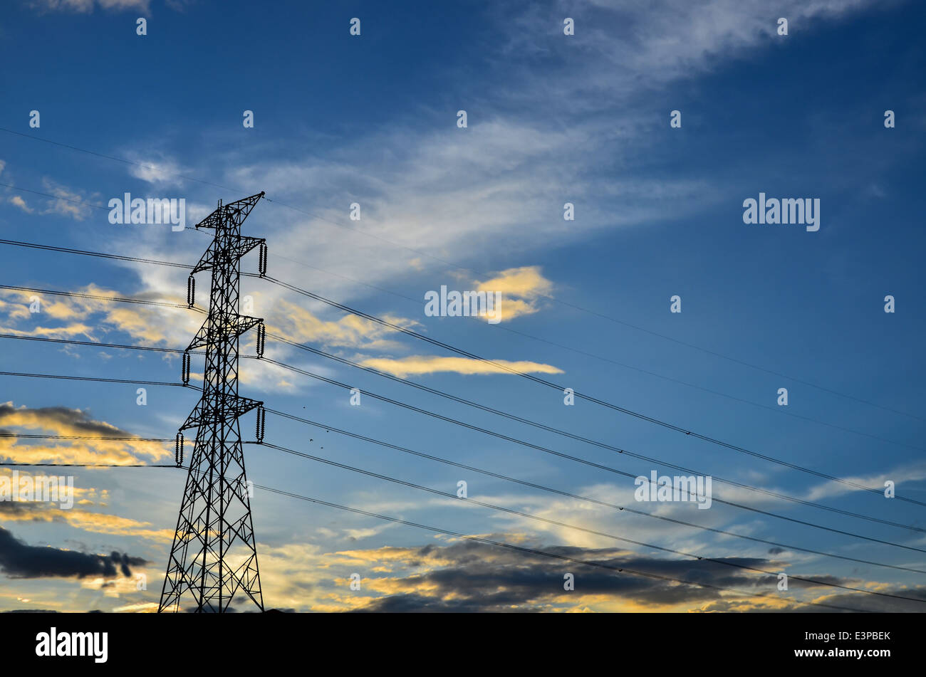 power tower silhouetted against blue sky and light clouds Stock Photo